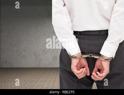 Composite image of  young businessman wearing handcuffs in grey room Stock Photo