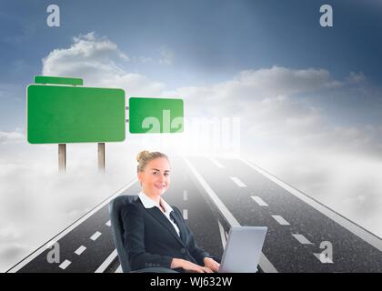 Composite image of businesswoman sitting in swivel chair with laptop on streets floating in sky Stock Photo