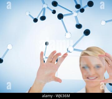 Composite image of doctor holding up clear pane and smiling in front of 3d molecules Stock Photo