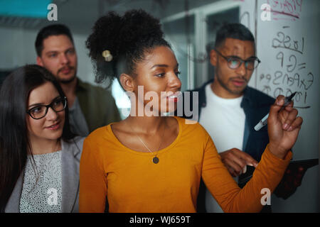 Multi-ethnic group of business people planning startup project on glass board in office Stock Photo