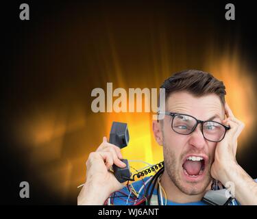 Composite image of frustrated computer engineer screaming while on call on black glowing background Stock Photo