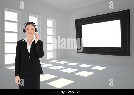 Composite image of good looking young woman in black suit using headphones and posing while standing Stock Photo