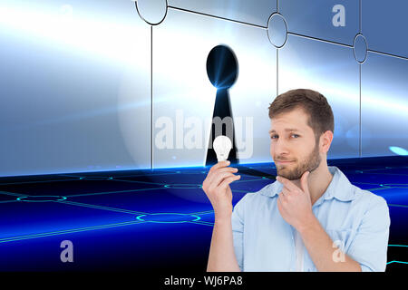 Composite image of handsome model holding a bulb Stock Photo