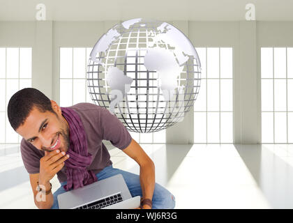 Composite image of thoughtful man sitting on floor using laptop and smiling at camera Stock Photo