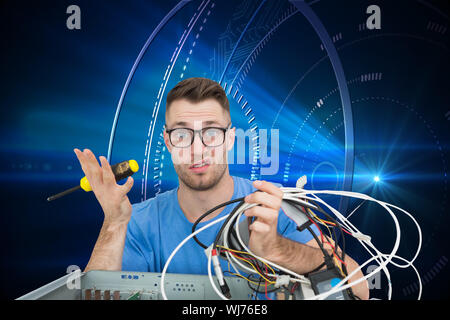 Composite image of portrait of confused young it professional with screw driver and cables in front of open cpu over white background Stock Photo