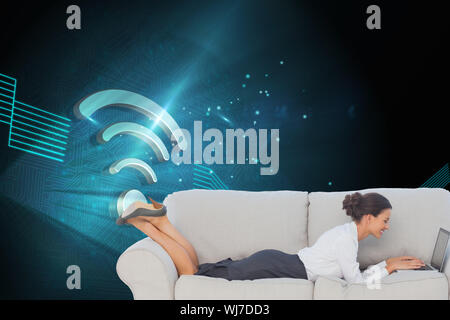 Composite image of smiling business woman lying on couch using laptop Stock Photo