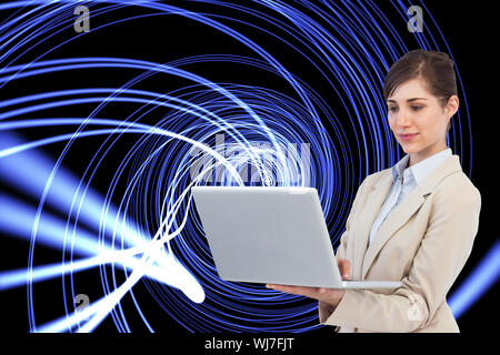 Composite image of confident businesswoman holding laptop Stock Photo