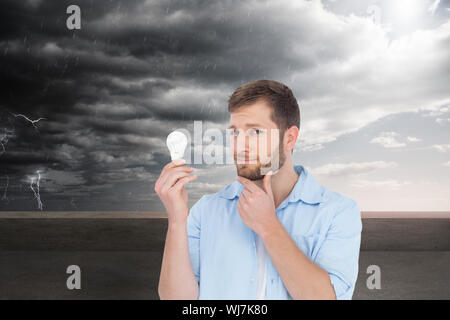 Composite image of handsome model holding a bulb Stock Photo