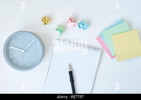 Gray round alarm clock colorful sticky notes and notebook on a white background, top view Stock Photo