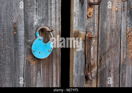 Blue old rusty unlocked padlock on wooden door Stock Photo
