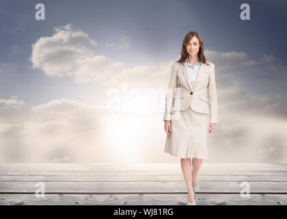 Composite image of smiling brunette businesswoman walking Stock Photo