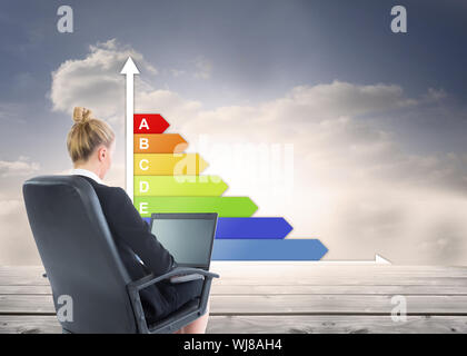 Composite image of blonde businesswoman sitting on swivel chair with laptop Stock Photo