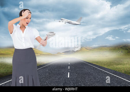 Composite image of surprised classy businesswoman holding newspaper while posing Stock Photo