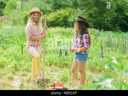 Agriculture concept. Growing vegetables. Hope for nice harvest. Sisters together helping at farm. Girls planting plants. Rustic children working in garden. Planting and watering. Planting vegetables. Stock Photo