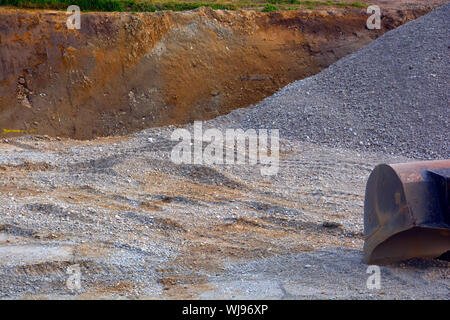 an excavator working removing gravel and sand on a construction site, sand in excavation pit Stock Photo