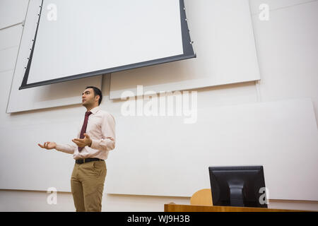 Elegant male teacher standing against projection screen in the lecture hall Stock Photo