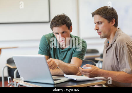 Two concentrated handsome mature students sitting in class while learning Stock Photo