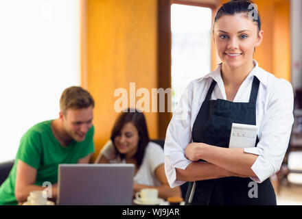 Portrait of a beautiful waitress with two students using laptop at  the coffee shop Stock Photo