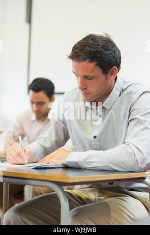 Mature students taking notes in lecture in college Stock Photo