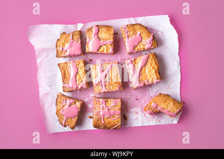 Pink chocolate brownie, sliced on baking paper and pink background. Above view of sliced ruby chocolate cake. Flat lay of a new chocolate dessert. Stock Photo