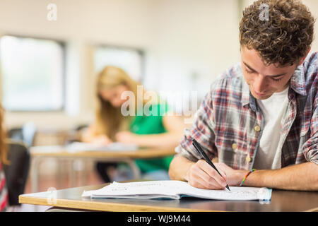Young male student with others writing notes in the classroom Stock Photo