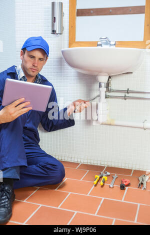 Focused plumber consulting tablet in public bathroom Stock Photo