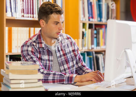 Handsome focused student using computer in library Stock Photo
