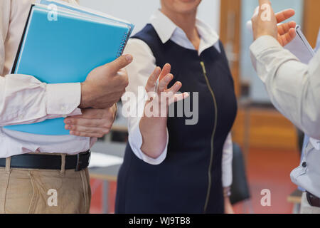 Mid section of mature students having a conversation in classroom Stock Photo