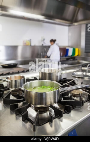Several pots cooking on hotplate in professional kitchen Stock Photo