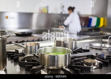 Different pots cooking on hotplate in professional kitchen Stock Photo