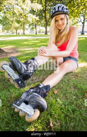 Casual gorgeous blonde wearing roller blades and helmet in a park Stock Photo