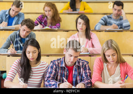 Concentrating students sitting at the lecture hall while writing Stock Photo