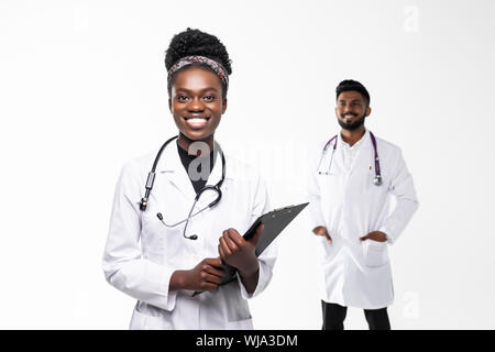 Intellectual healthcare professional afro american doctor with collegue using digital tablet on gradient background. Stock Photo