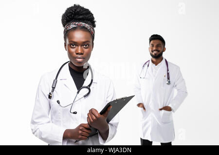 Intellectual healthcare professional afro american doctor with collegue using digital tablet on gradient background. Stock Photo