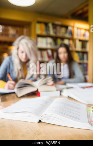 Two blurred students writing notes at desk in the college library Stock Photo