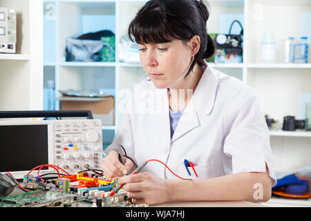 Tech tests electronic equipment in service centre Stock Photo