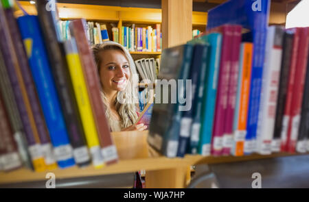 Portrait of a smiling young female amid bookshelves in the college library Stock Photo