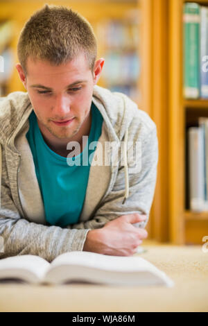Close up of a serious male student reading book on the college library floor Stock Photo