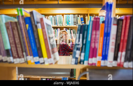 Portrait of a smiling young female amid bookshelves in the college library Stock Photo