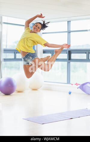 Young woman jumping in fitness studio Stock Photo