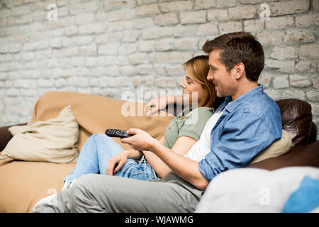Smiling lovely young couple relaxing and watching TV at home Stock Photo