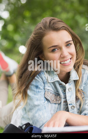 Smiling young student lying on grass Stock Photo