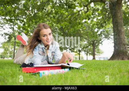 Happy young student lying on the grass studying Stock Photo