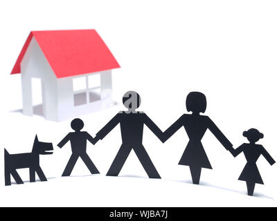 A paper family is holding hands beside their new paper house. Even the paper dog is there. Stock Photo