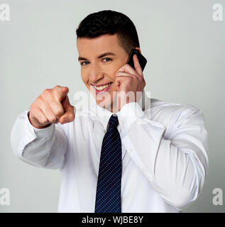 Businessman communicating through mobile and pointing you Stock Photo