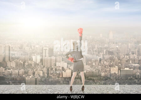 Young attractive asian business woman with boxing gloves are ready for battle. Rear view. Stock Photo