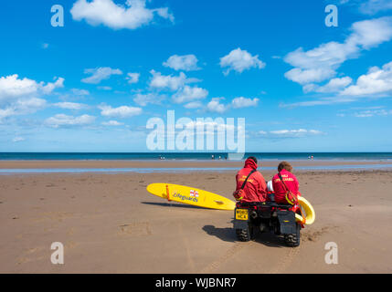Rear view of two RNLI lifeguards sitting on quad bike Stock Photo