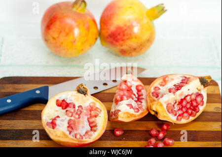 fresh pomegranate fruit over wood cutting board with knife Stock Photo