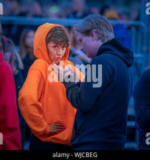 Teenage girl posing for the camera, boy using his phone, Menningarnott or Cultural day, Reykjavik, Iceland. Stock Photo