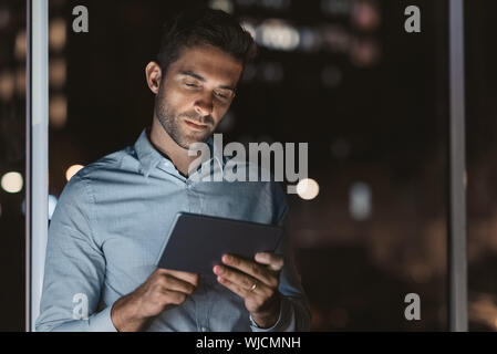 Handsome businessman using a tablet in his office at night Stock Photo